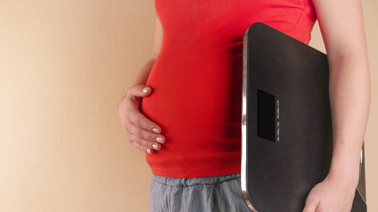 Femme se tenant le ventre et tenant une balance