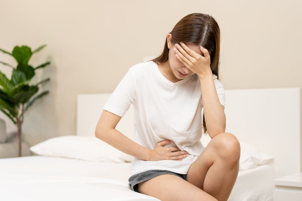 Femme qui se tient la tête et le ventre